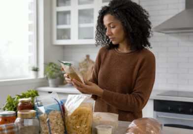 Seseorang memeriksa tabel Informasi Nilai Gizi pada kemasan makanan di meja dapur
