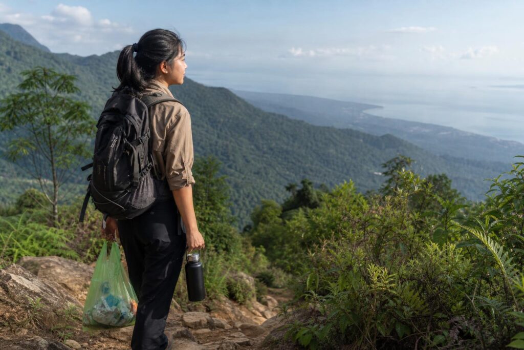 Wisatawan membawa botol minum guna ulang dan kantong sampah di jalur wisata alam
