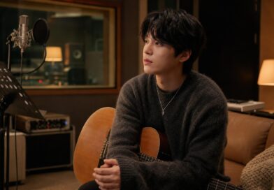Penyanyi solo duduk di studio rekaman dengan gitar akustik dalam suasana hangat dan tenang