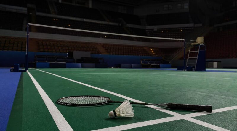Lapangan bulu tangkis kosong di arena Asian Games dengan raket dan kok di dekat garis lapangan
