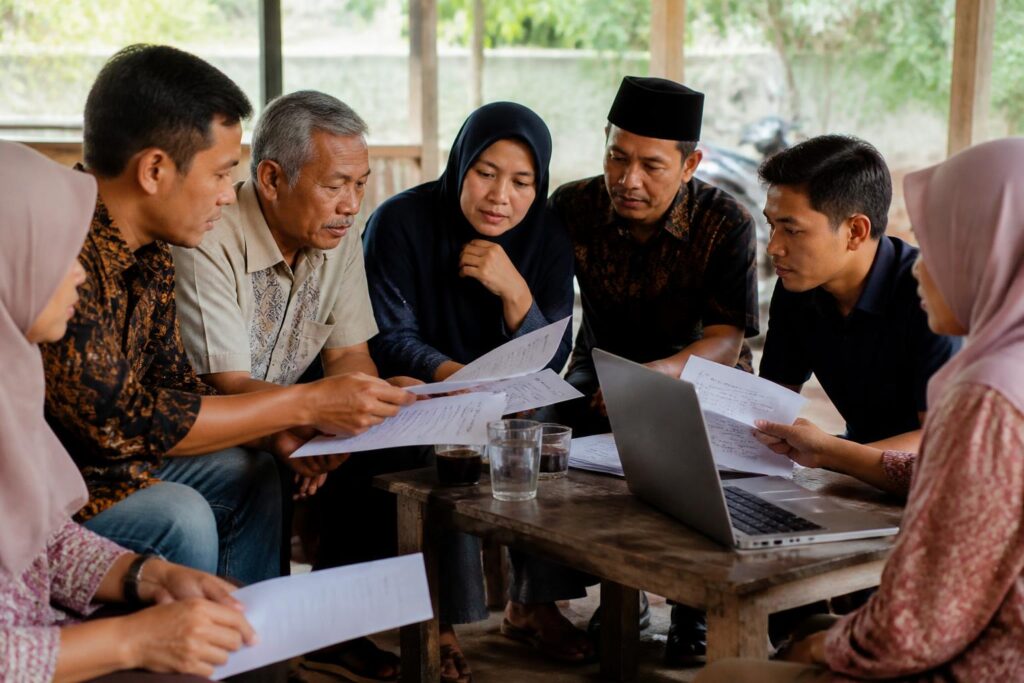 Warga berdiskusi sambil membaca dokumen rancangan undang-undang di depan laptop