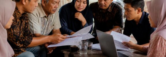 Warga berdiskusi sambil membaca dokumen rancangan undang-undang di depan laptop