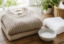 Sweater rajut terlipat di samping handuk dan perlengkapan deterjen lembut untuk perawatan pakaian
