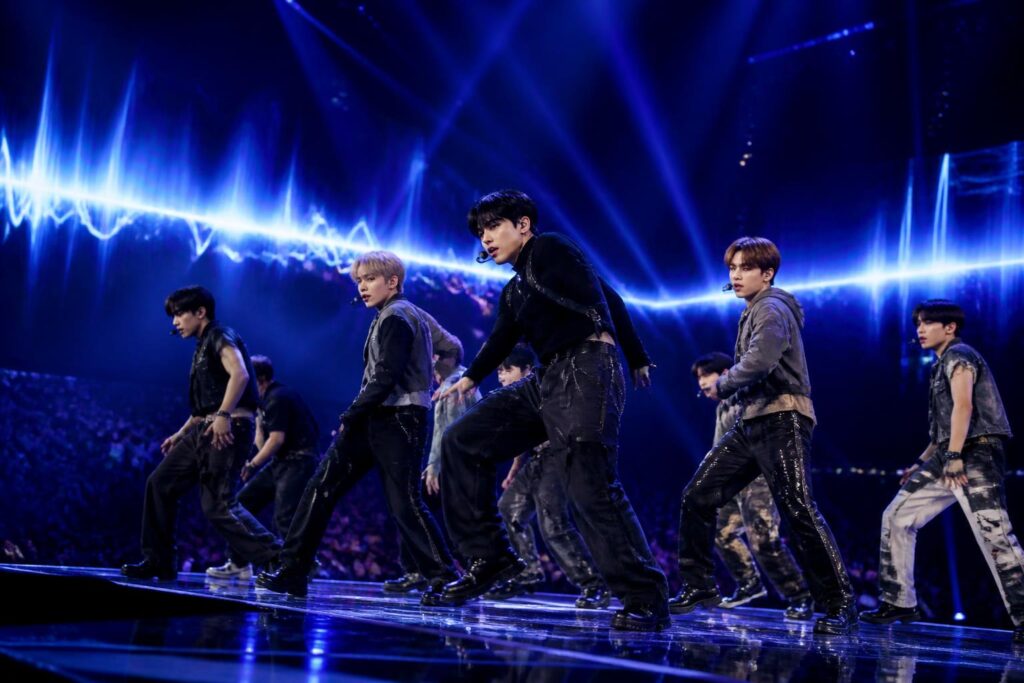 Penampilan grup K-Pop di atas panggung dengan pencahayaan biru dan ungu yang dramatis