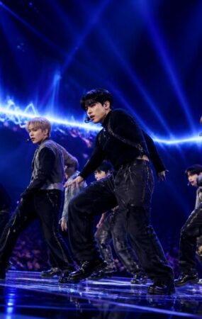Penampilan grup K-Pop di atas panggung dengan pencahayaan biru dan ungu yang dramatis