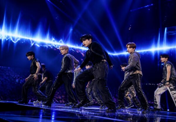 Penampilan grup K-Pop di atas panggung dengan pencahayaan biru dan ungu yang dramatis