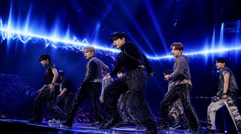 Penampilan grup K-Pop di atas panggung dengan pencahayaan biru dan ungu yang dramatis