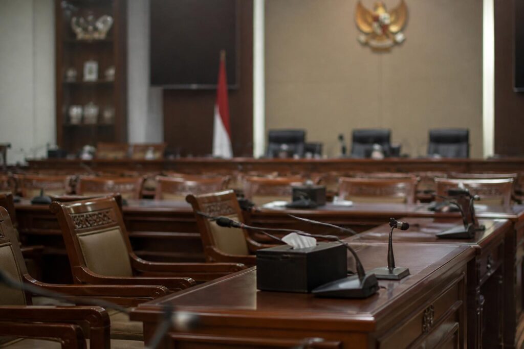 Ruang rapat komisi parlemen Indonesia dengan meja dan mikrofon dalam suasana pemberitaan politik