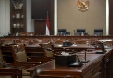 Ruang rapat komisi parlemen Indonesia dengan meja dan mikrofon dalam suasana pemberitaan politik