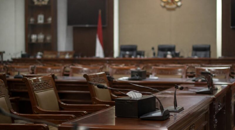 Ruang rapat komisi parlemen Indonesia dengan meja dan mikrofon dalam suasana pemberitaan politik