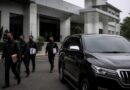 Ilustrasi penyidikan KPK dengan kendaraan SUV di depan gedung perkantoran pemerintahan