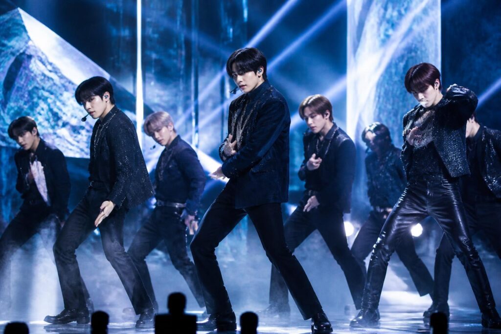Penampilan grup K-pop di panggung dengan pencahayaan biru dan perak dalam suasana showcase comeback
