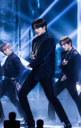 Penampilan grup K-pop di panggung dengan pencahayaan biru dan perak dalam suasana showcase comeback