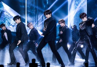 Penampilan grup K-pop di panggung dengan pencahayaan biru dan perak dalam suasana showcase comeback