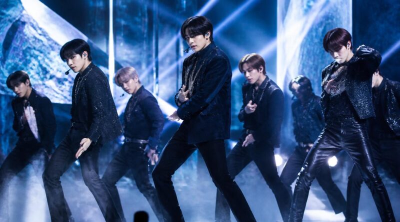 Penampilan grup K-pop di panggung dengan pencahayaan biru dan perak dalam suasana showcase comeback