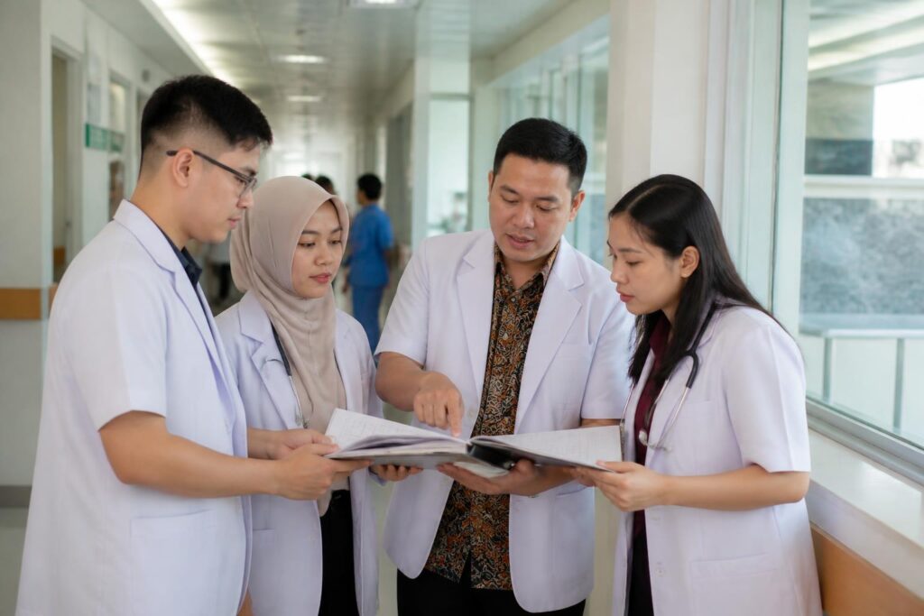 Dokter residen dan pembimbing berdiskusi di koridor rumah sakit pendidikan