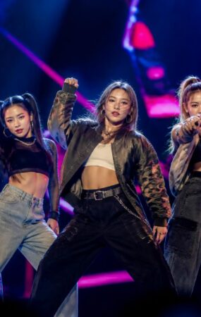 Grup perempuan K-pop tampil dengan koreografi energik di atas panggung dalam suasana konser tur internasional