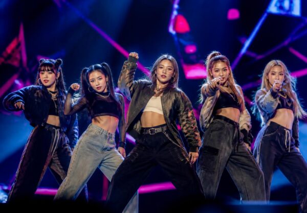 Grup perempuan K-pop tampil dengan koreografi energik di atas panggung dalam suasana konser tur internasional
